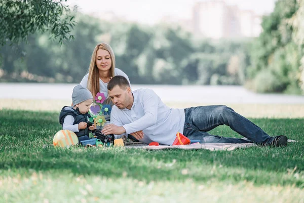 Rodiče si hrají s malým synem sedícího v trávě — Stock fotografie