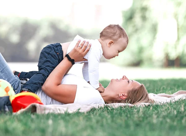 Moeder en haar zoontje spelen samen, liggend op het gazon . — Stockfoto