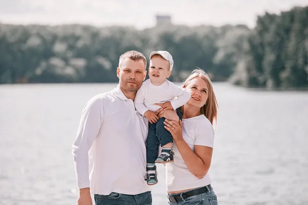 Retrato de una familia joven sobre un fondo de lago — Foto de Stock