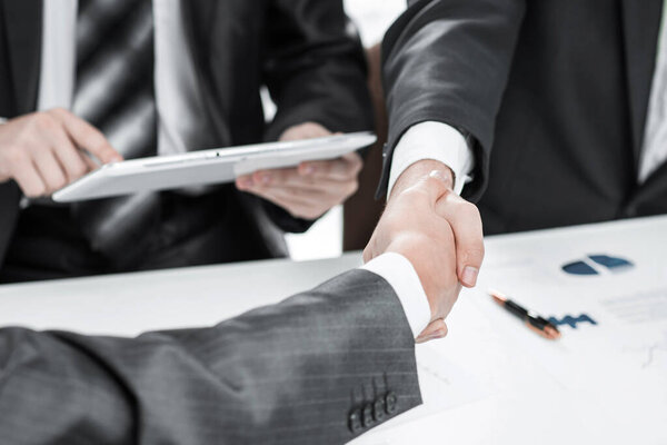 close up.the financial partners shaking hands over a Desk