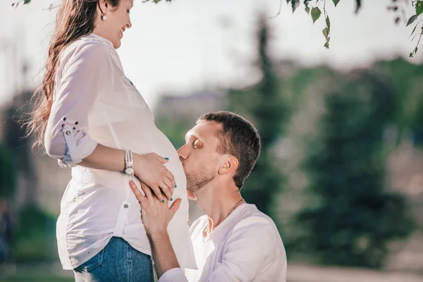 Feliz marido besando a sus esposas embarazadas vientre . —  Fotos de Stock