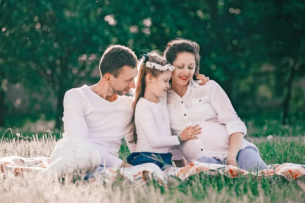 Glückliche Familie sitzt auf dem Gras an einem Sommertag. — Stockfoto