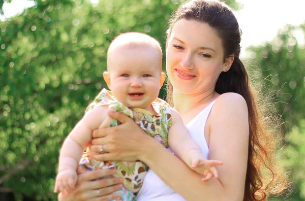 Jovem mulher com um bebê em um fundo da cidade Park — Fotografia de Stock