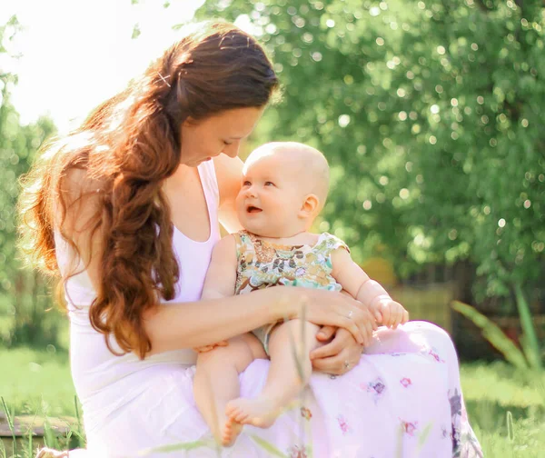 Mom talking to the baby sitting on a bench in the Park — Stock Photo, Image