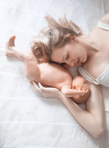 Feliz mamá abraza a su hija recién nacida acostada en la cama  . —  Fotos de Stock