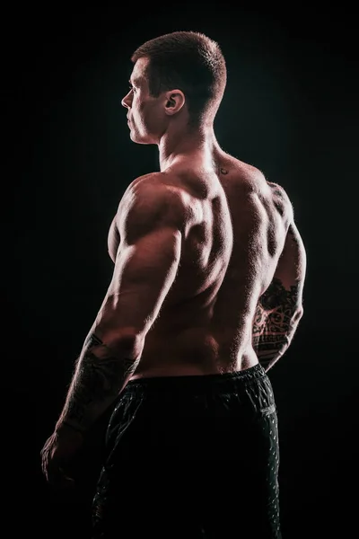 Πίσω όψη. όμορφος αρσενικό bodybuilder. απομονωμένο σε μαύρο — Φωτογραφία Αρχείου