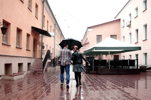 Vista trasera. pareja amorosa en la calle en un día lluvioso — Foto de Stock