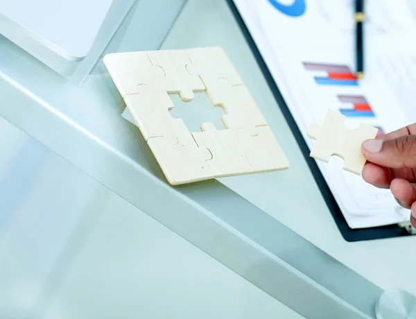 Close-up. de zakenman is een puzzel, zitten achter een bureau. — Stockfoto