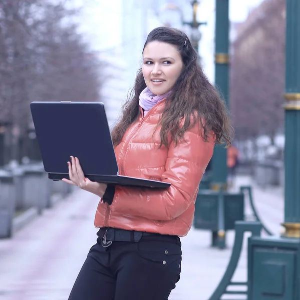 Smiling young woman blogger with laptop on city street — Stock Photo, Image