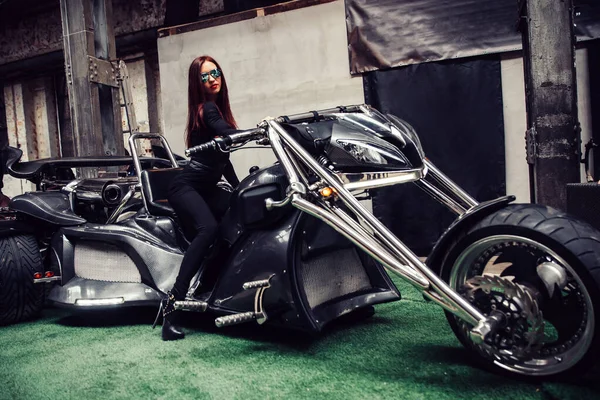 Stylisches junges Frauenmodel posiert in der Nähe eines schicken Dreirads. — Stockfoto