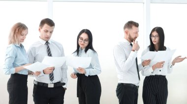 İş dünyası ekibi ofis koridorunda duran iş belgelerini tartışıyor.