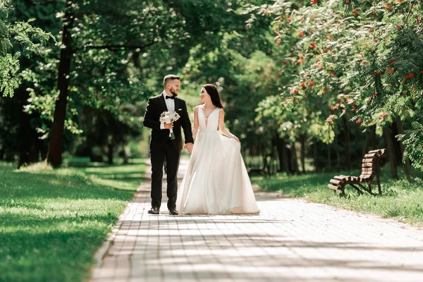 Belo casal amoroso andando ao longo do caminho no parque da cidade . — Fotografia de Stock