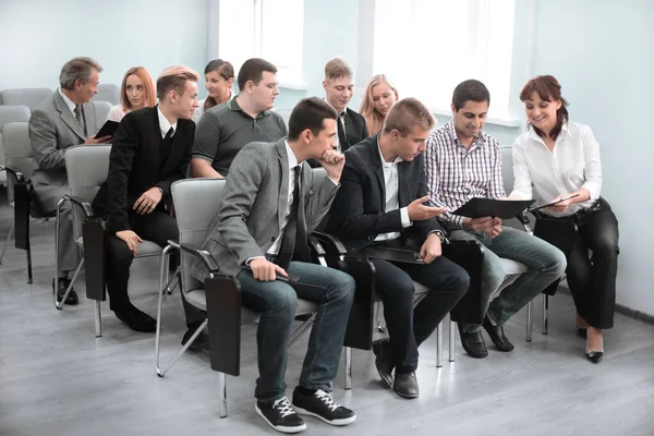 Grupp affärsmän i formalwear sitter vid stolarna i konferenssalen — Stockfoto