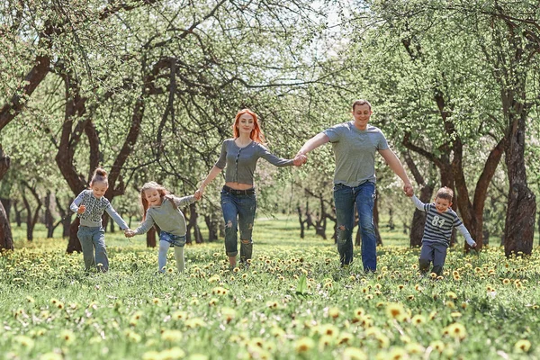 Familia con niños caminando sobre la hierba en el jardín de primavera —  Fotos de Stock