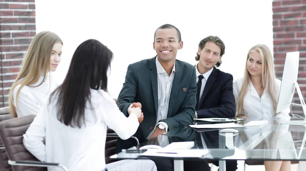Apretón de manos a las mujeres de negocios con su socio en la mesa de negociaciones — Foto de Stock
