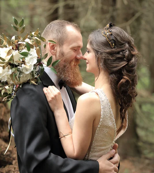 Sposo abbraccia la sposa in una pineta — Foto Stock
