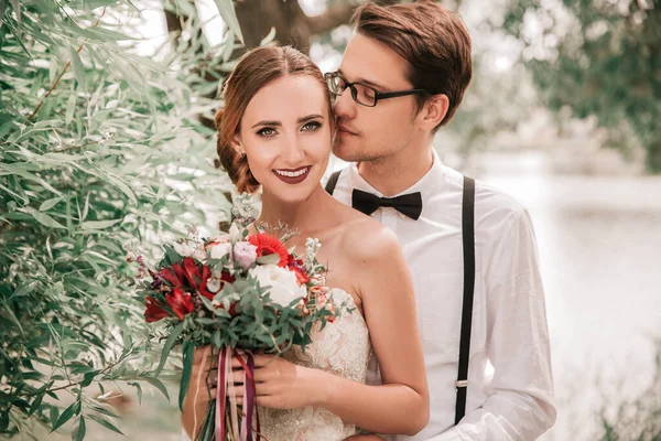 Glücklicher Bräutigam küsst seine Braut im Stadtpark — Stockfoto