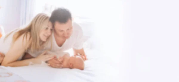 Retrato de uma família feliz com um bebê recém-nascido. fundo para texto em borrão com espaço de cópia — Fotografia de Stock