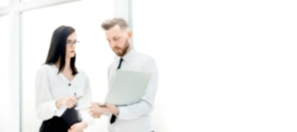 Business couple uses a laptop while standing in the office. background for text in blur with copy space — Stock Photo, Image