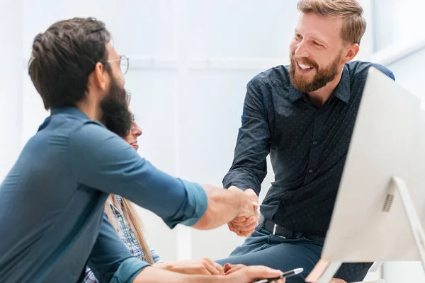 Young employees shaking hands in the workplace — Stock Photo, Image