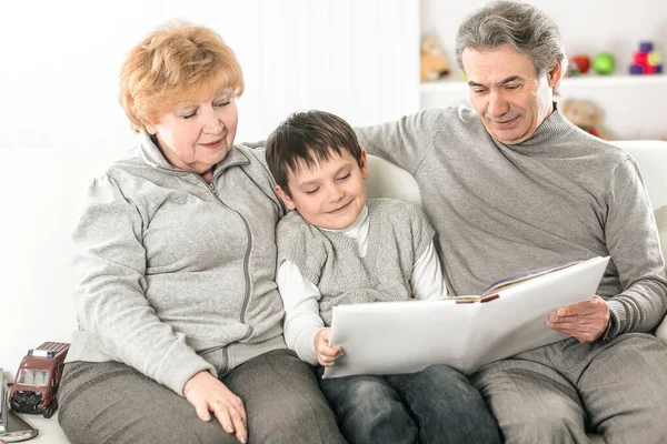 Любящие бабушка и дедушка с внуком, сидящими на диване — стоковое фото