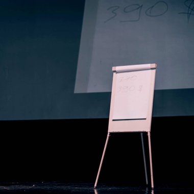 Seminerin podyumunda bir ters grafik ve geniş ekran var.