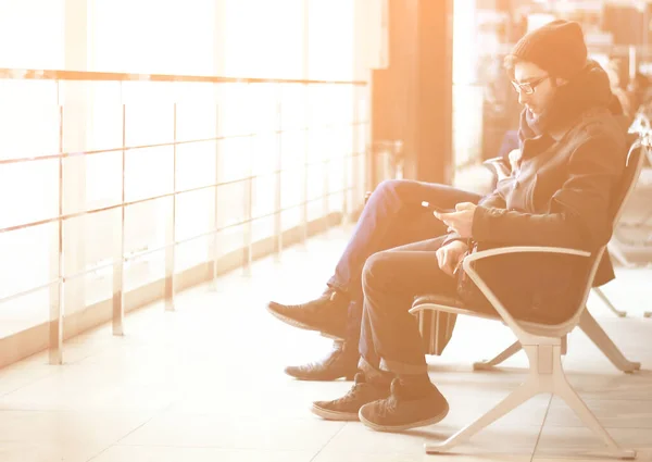 Close up.modern uomo con smartphone seduto nella sala d'attesa dell'aeroporto — Foto Stock