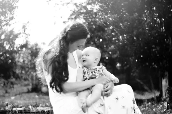 Mamá hablando con el bebé sentado en un banco en el parque. foto en blanco y negro — Foto de Stock