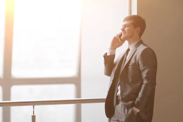 Stäng up.businessman talar på smartphone när du står nära ett fönster i office — Stockfoto