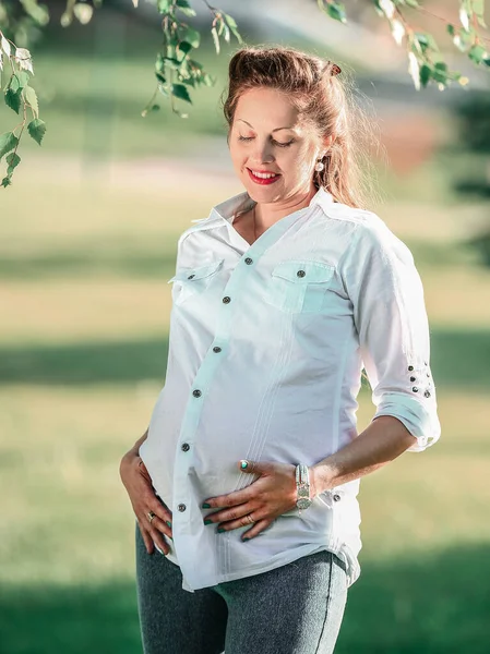 Giovane donna incinta in una passeggiata nel parco in una giornata di sole — Foto Stock