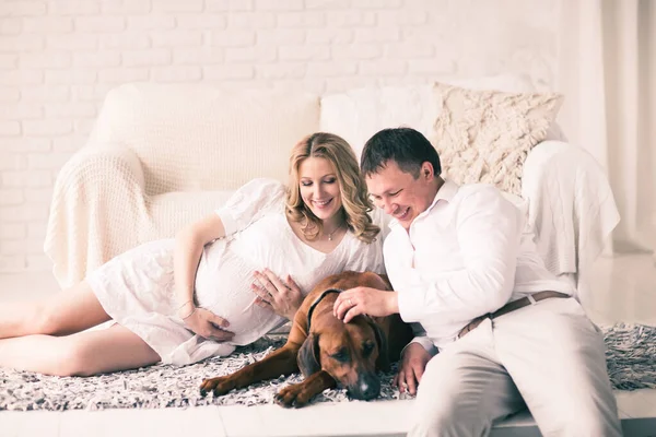 Marido, esposa embarazada y perro descansando en la cama con el bedro — Foto de Stock
