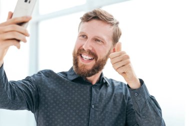 Mutlu iş adamı akıllı telefonuyla video bağlantısı kuruyor.