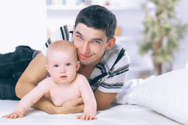 Genç baba kanepede çocuğuyla oynuyor.