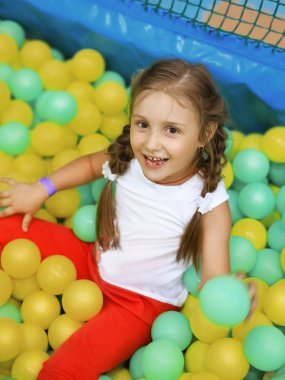 Oyun bahçesinde renkli balonları olan küçük bir kız.