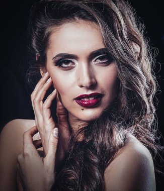 Akşam makyajıyla yüzüne dokunan göz kamaştırıcı genç kadın..