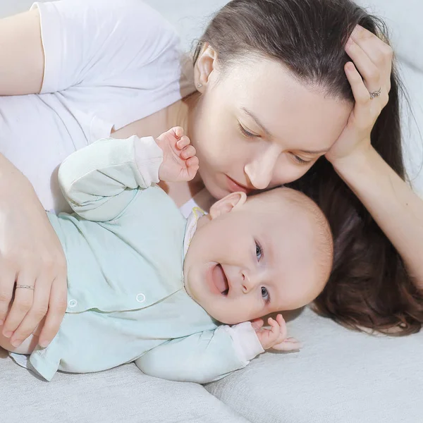 Close up.mom and baby lying on the couch and looking at the came — Stock Photo, Image