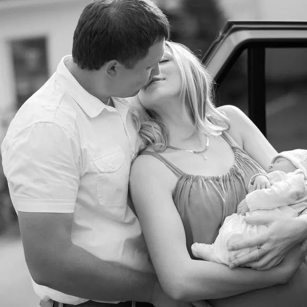 Marido feliz besando a su esposa con un bebé recién nacido —  Fotos de Stock