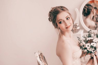 Gelin elinde buketle aynanın önünde oturuyor.