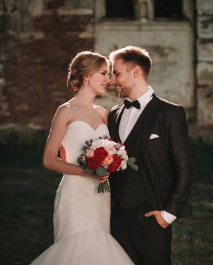 Gelin ve bir buket düğün ve damat eski malikanenin yanında duruyor.