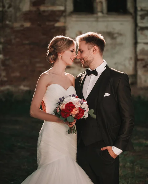 Mariée avec un bouquet de mariage et le marié debout près du vieux manoir — Photo