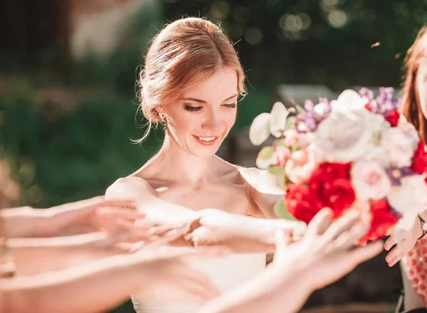 Lächelnde Braut reicht Hochzeitsstrauß an ihre Freunde. — Stockfoto