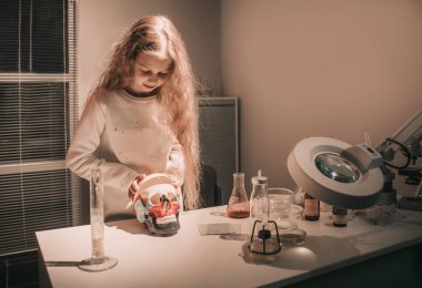 Kız öğrenci insan kafatasının yapısını inceliyor.