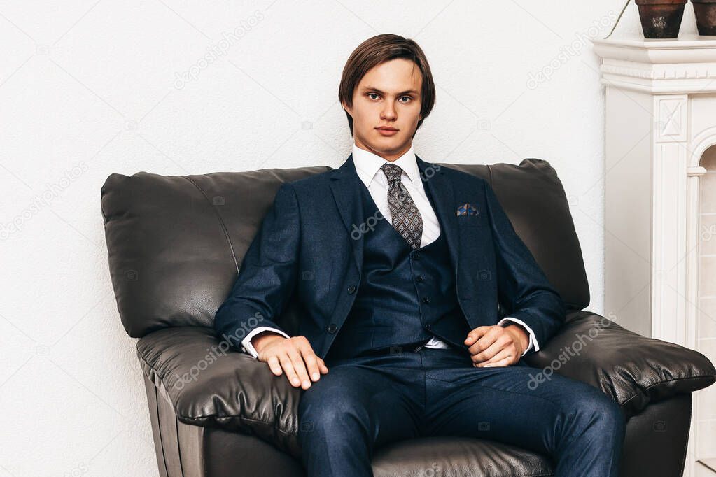 successful young businessman sitting in a chair near the fireplace.