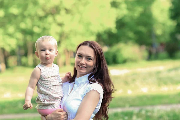 Mutter mit ihrer süßen kleinen Tochter auf einem verschwommenen Hintergrund der Natur. — Stockfoto