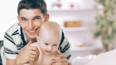 Genç baba kanepede çocuğuyla oynuyor.