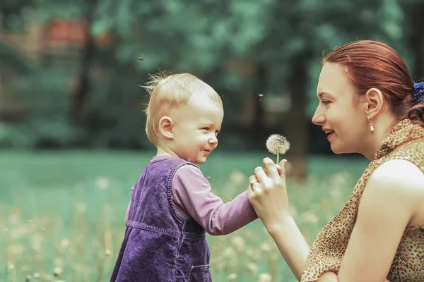 Young mother teaches her little daughter to blow on a dandelion — Stock Photo, Image