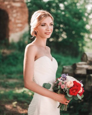 Bir buket çiçekli gelin Park 'ın bulanık arka planında.