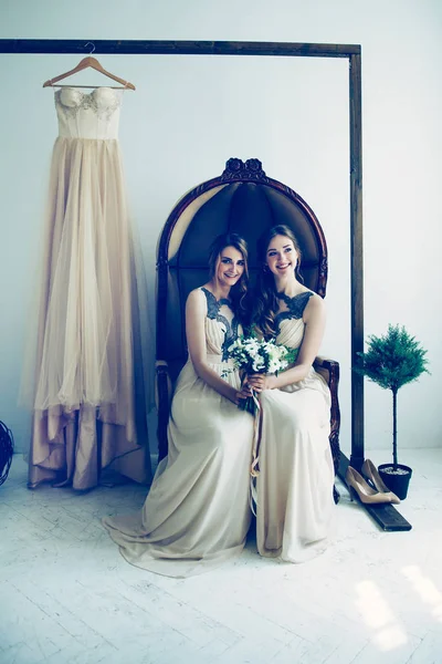 Dos damas de honor con un ramo de bodas sentado en una silla — Foto de Stock