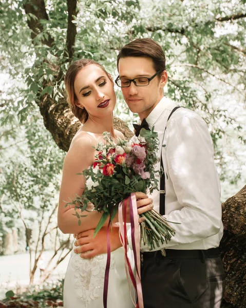 Porträtt av glada nygifta på bakgrunden av vårskogen. — Stockfoto