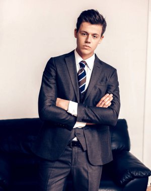 İş merkezinin odasında belgeli genç bir işadamı duruyor.